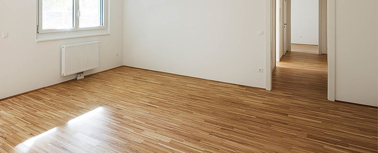 Eine leere Eigentumswohnung mit Parkettboden.